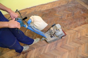 Håndværker er i gang med at afhøvle gulv med sildebensparket - gulvafslibning