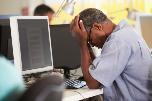 Mand tager sig til hovedet foran en computer
