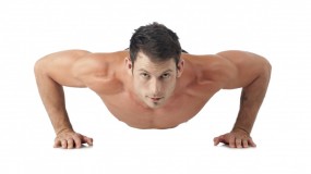 Muskuløs mand i bar overkrop laver armstrækninger