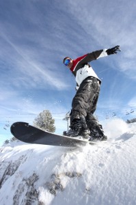 SNowboarder på vej ud over bakke med blå himmel i baggrunden