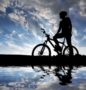 Ung mand på mountainbike i silhouet foran en blå himmel