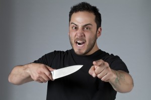 Vred mand i sort t-shirt med kokkekniv