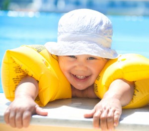 Lille dreng med gule svømmevinger i swimming pool