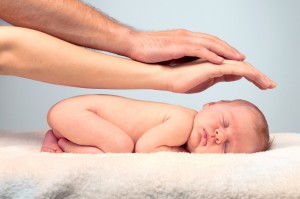 To hænder holdes beskyttende over en sovende baby