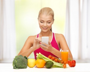 Ung kvinde tæller kalorier foran en masse sunde grøntsager