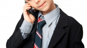 Dreng i jakkesæt med slips taler i mobiltelefon